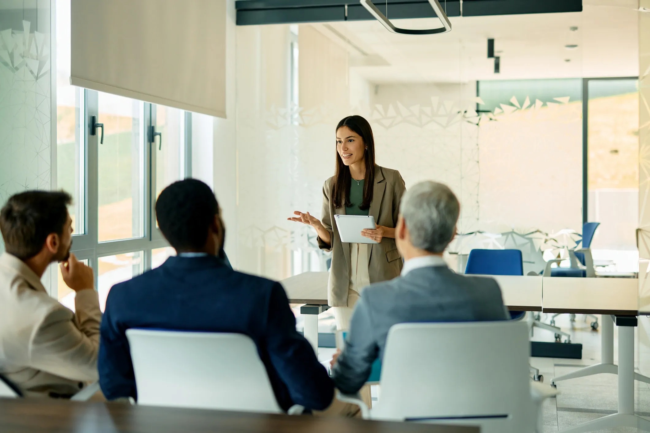 Young businesswoman holding a tablet and leading a meeting in a modern office